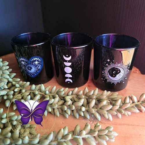 Set van drie blauwe waxinelichthouders met spirituele designs – hart, maanstanden en zon/maan – op houten ondergrond met groene takjes en Evylin Design logo